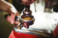 waitress-using-a-tamper-to-press-ground-coffee-into-a-portafilter_1170-570